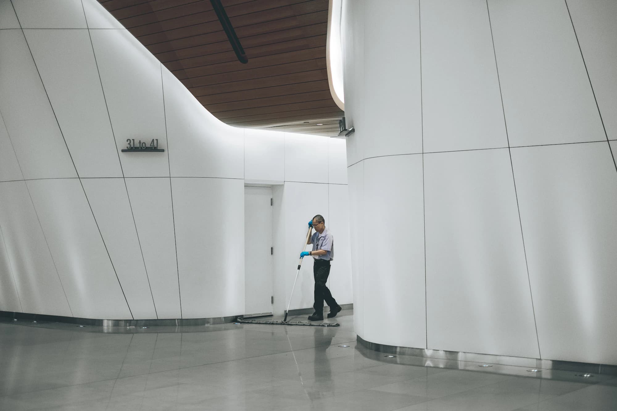 Cleaner working alone in a bright white lobby
