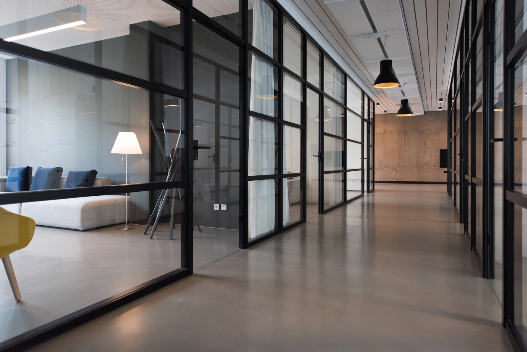 Glass-walled office corridor with a polished concrete floor